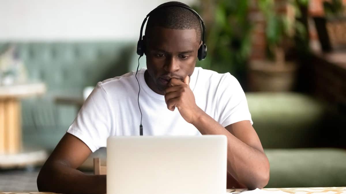 Young Black man sat in front of laptop while wearing headphones