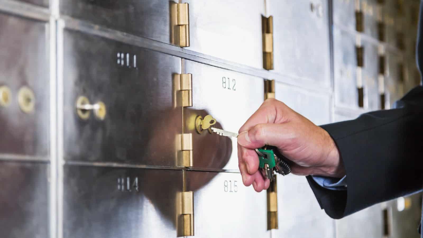 Hand of a mature man opening a safety deposit box.