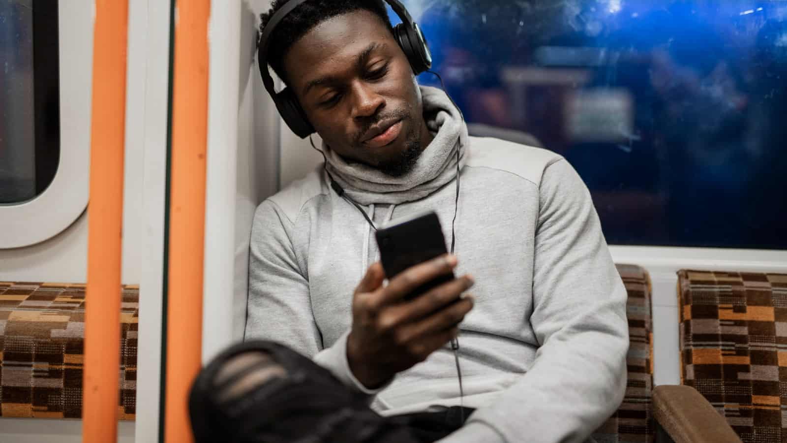 Young black man looking at phone while on the London Overground