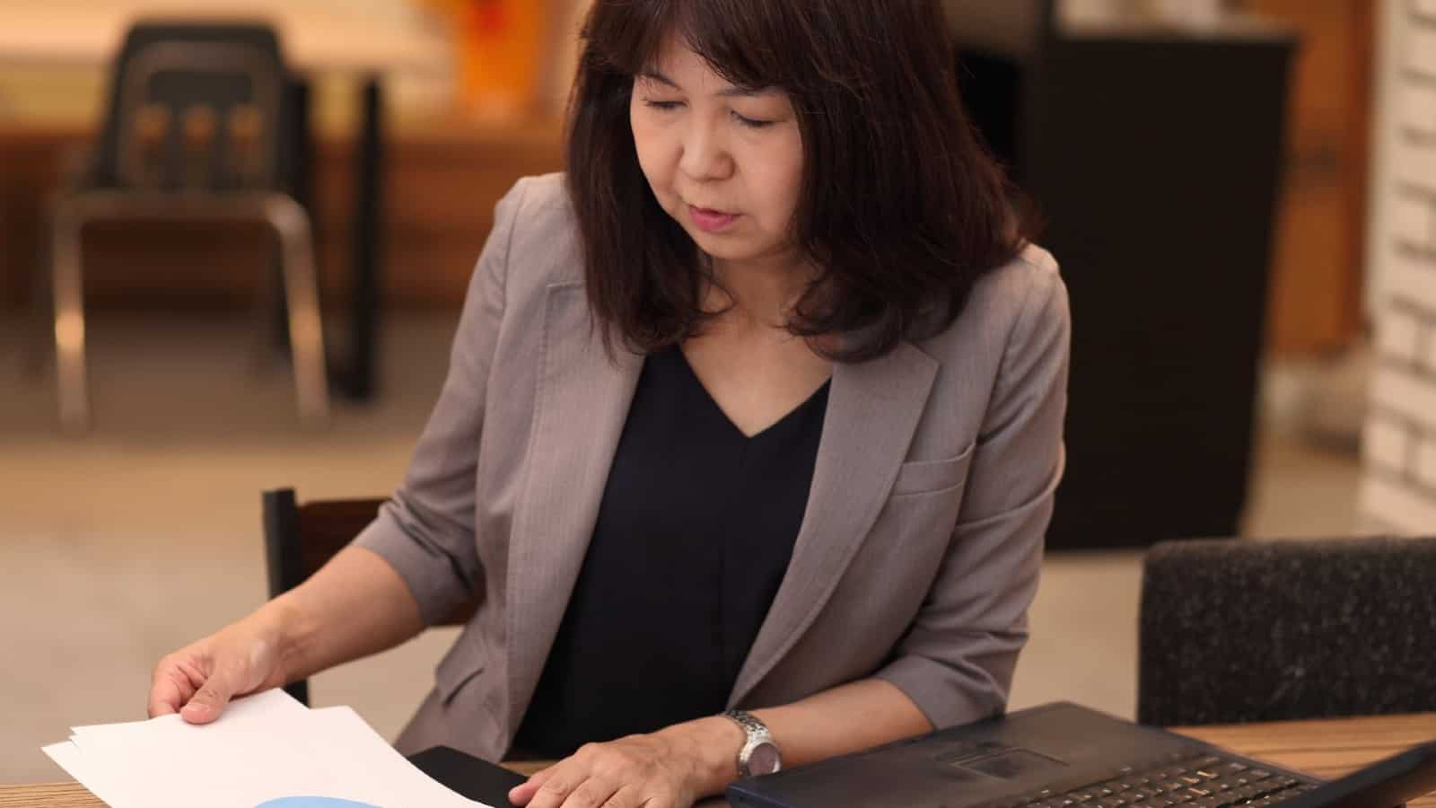 Female analyst sat at desk looking at pie charts on paper