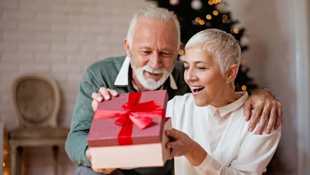 Elderly man giving a Christmas present to his wife