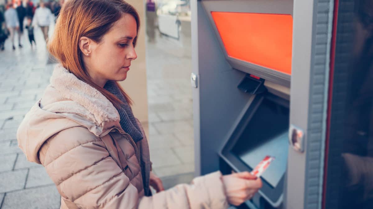 Young Caucasian woman at the street withdrawing money at the ATM