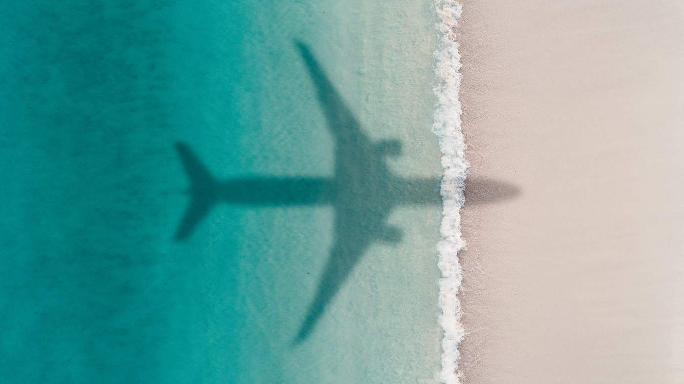 Aerial shot showing an aircraft shadow flying over an idyllic beach