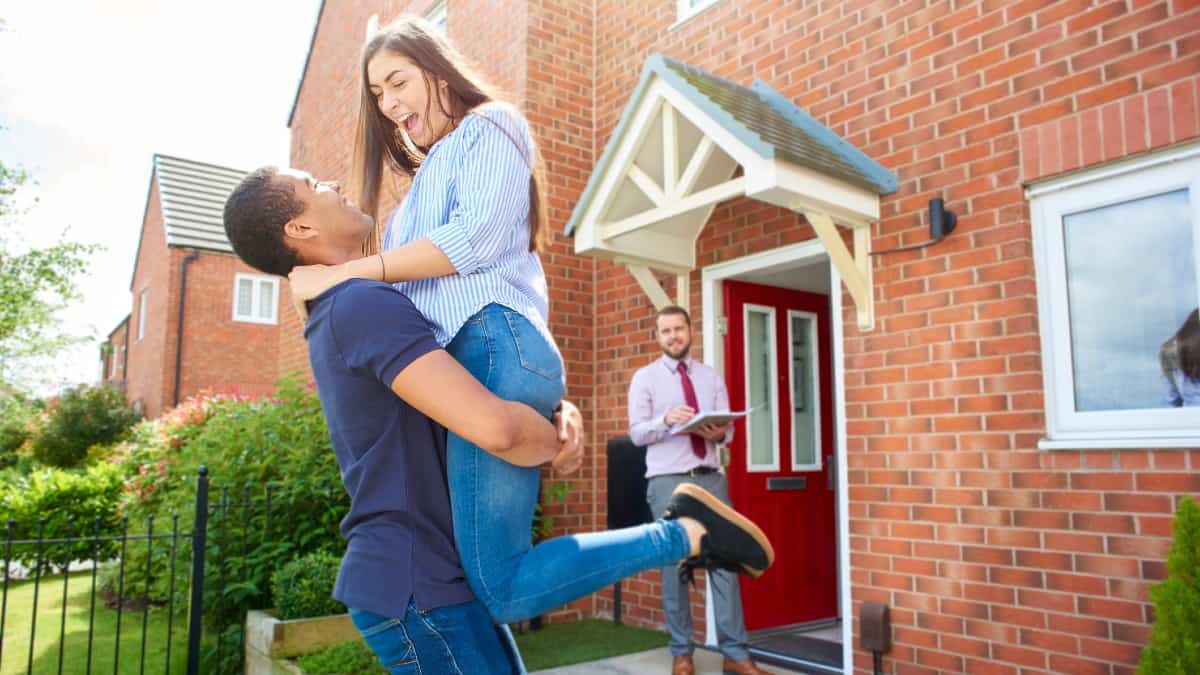 a couple embrace in front of their new home