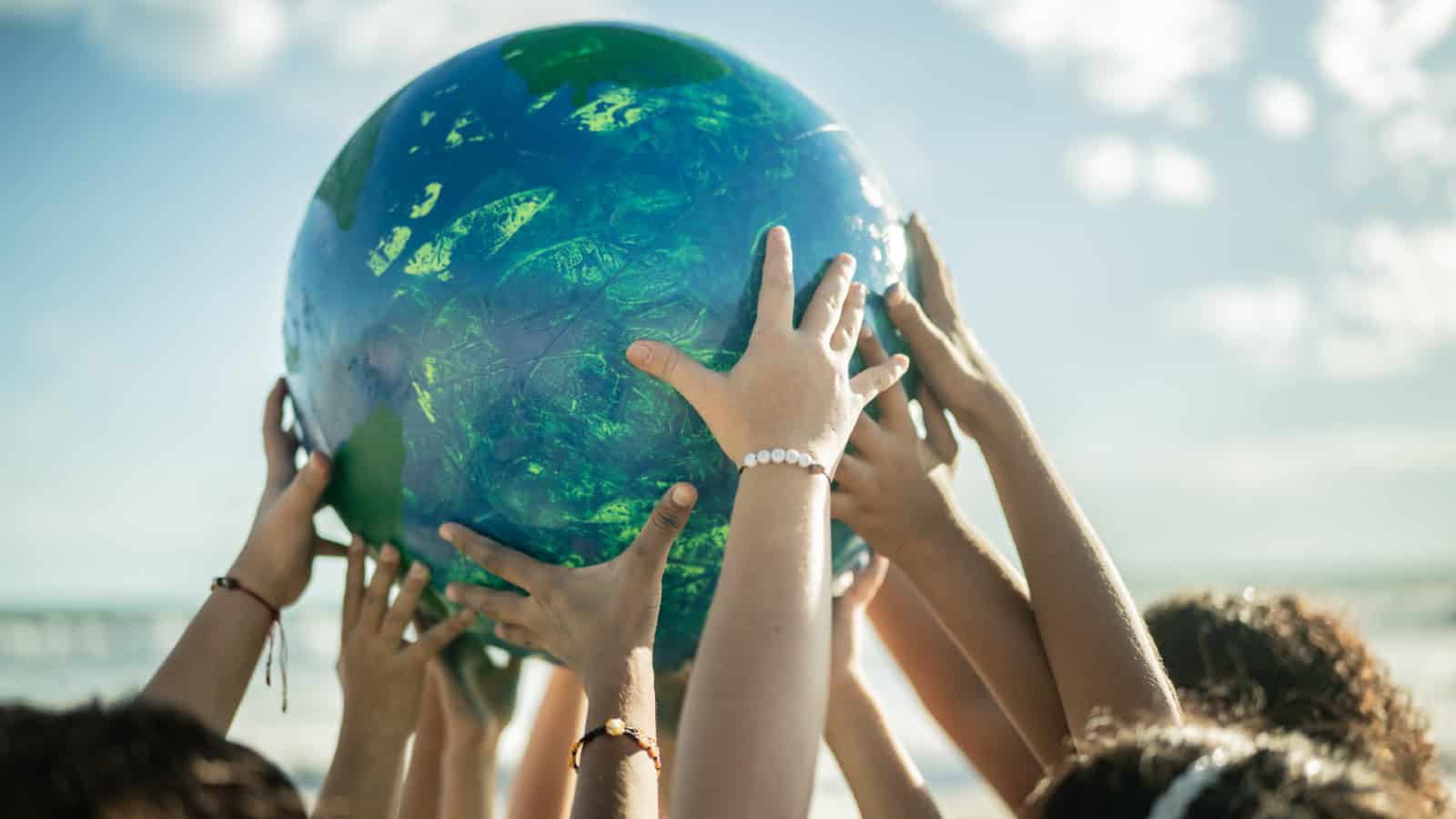 Close-up of children holding a planet at the beach