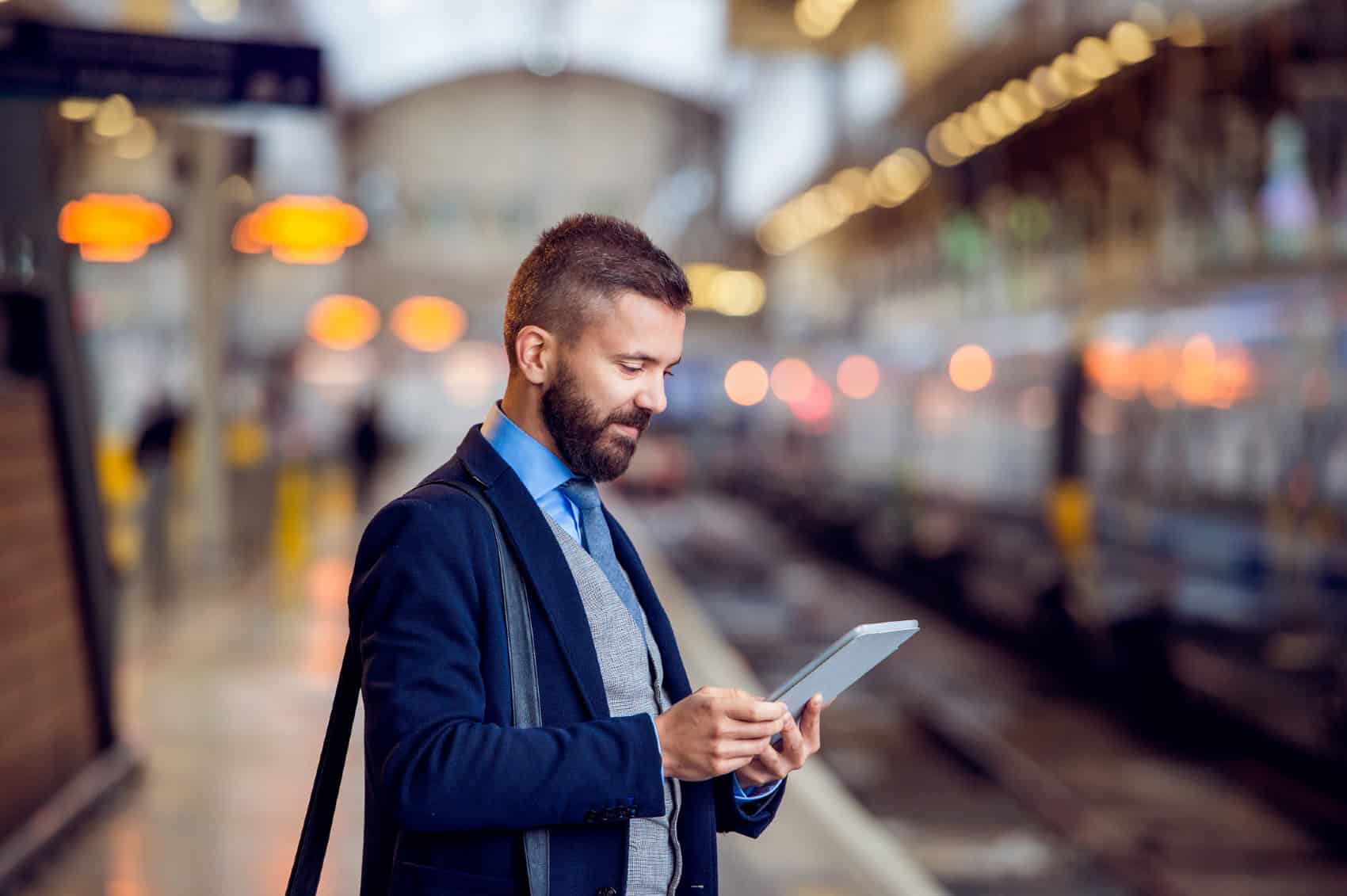 Businessman with tablet, waiting at the train station platform