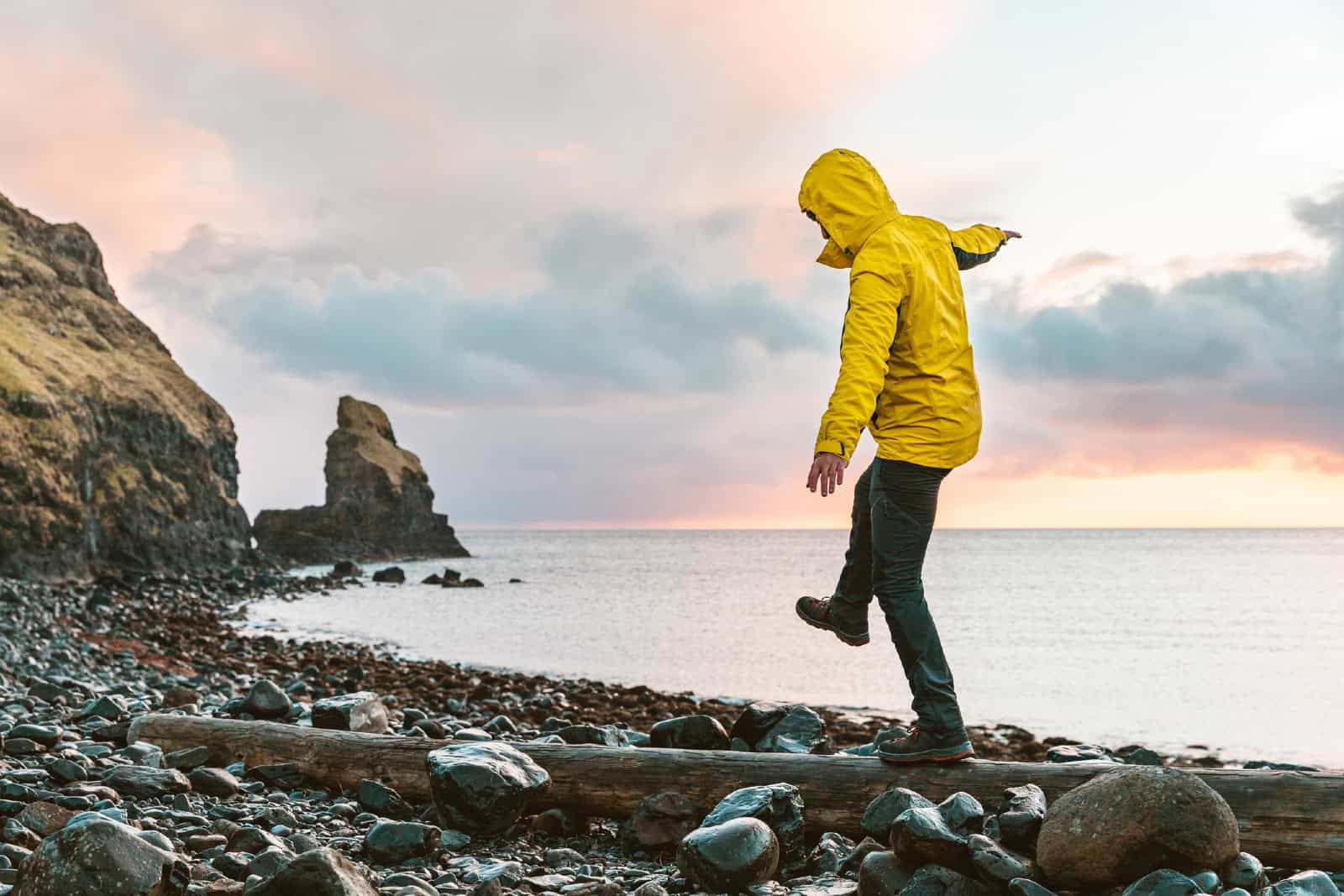 Man hanging in the balance over a log at seaside in Scotland
