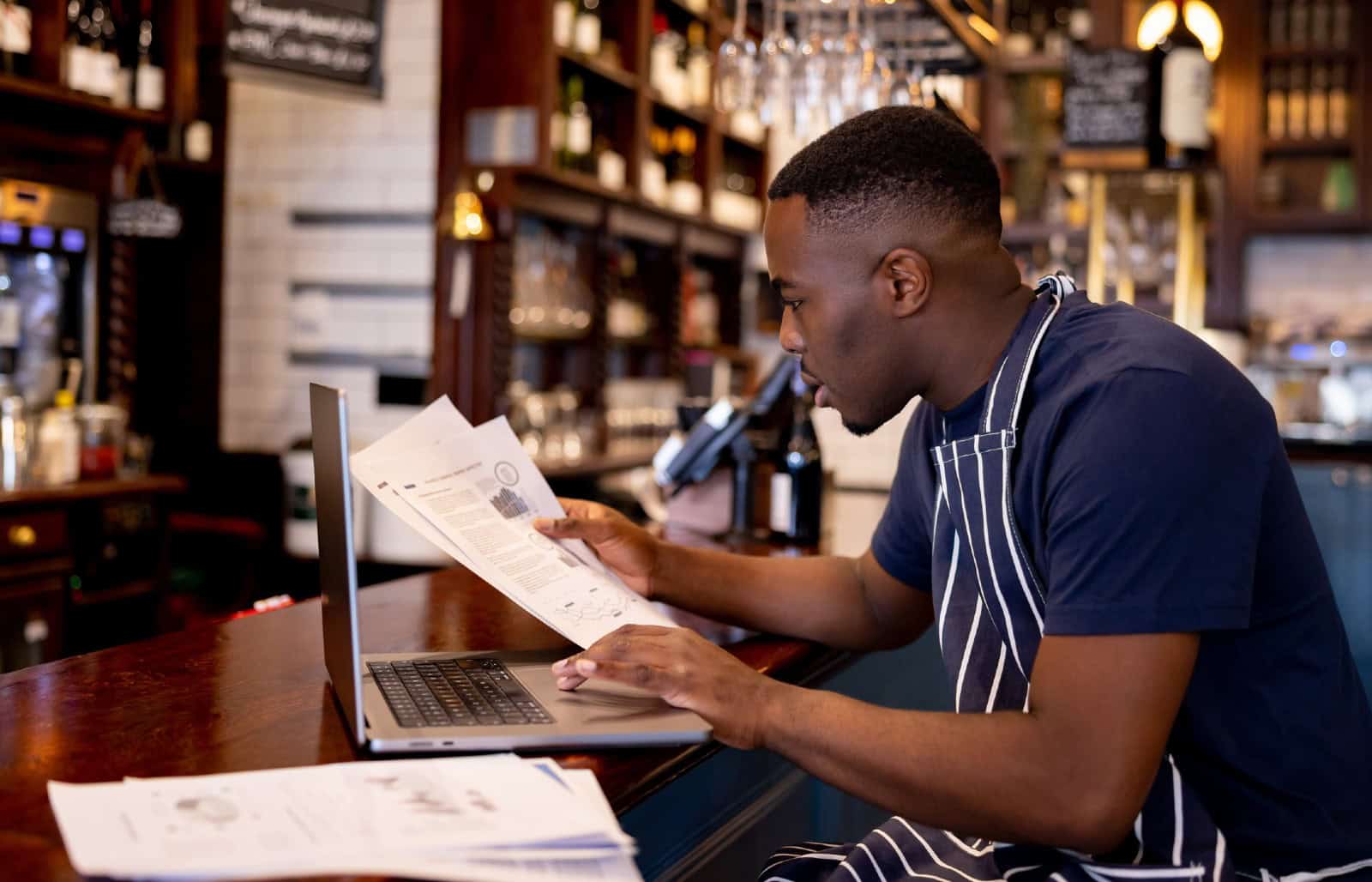 Business manager working at a pub doing the accountancy and some paperwork using a laptop computer