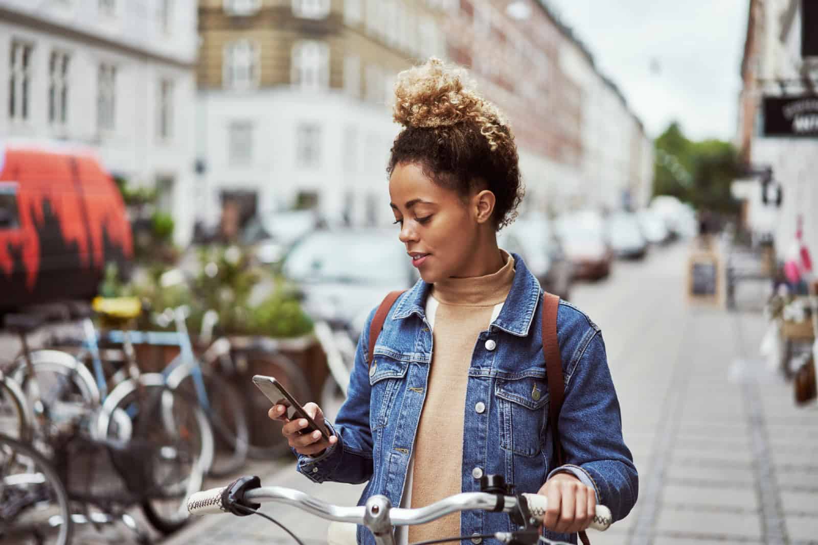 Shot of an young mixed-race woman using her cellphone while out cycling through the city