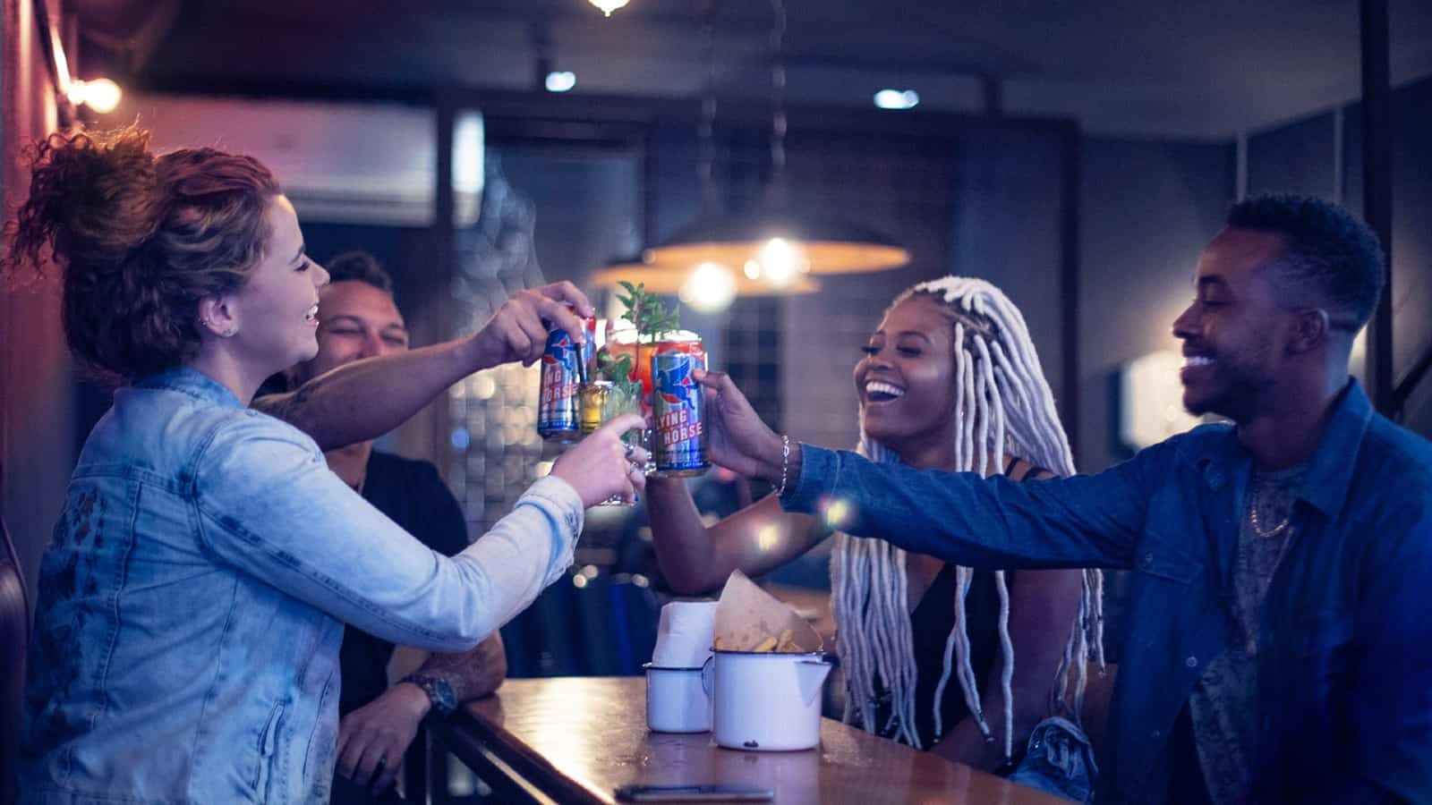 Group of four young adults toasting with Flying Horse cans in Brazil
