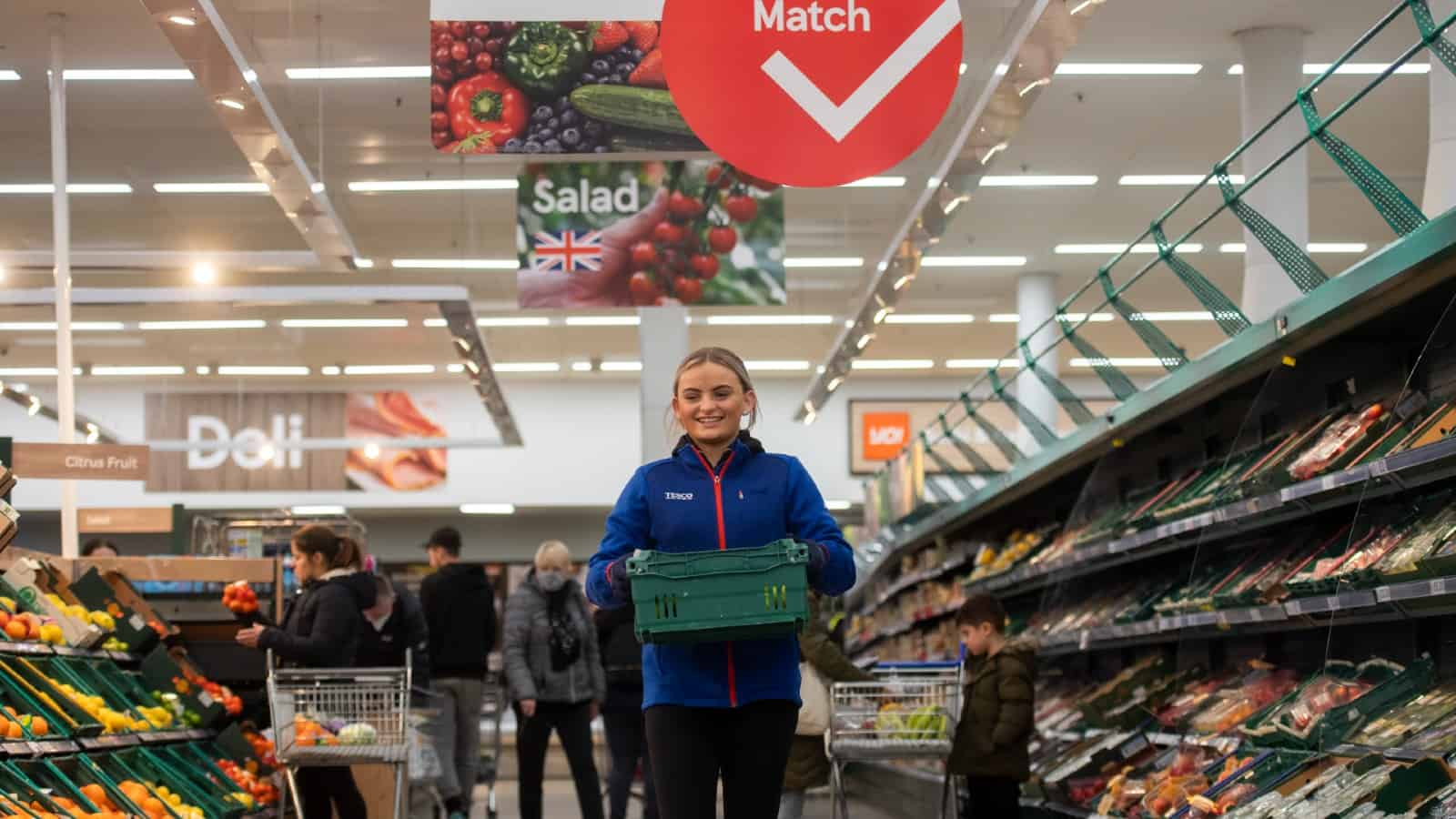 Female Tesco employee holding produce crate