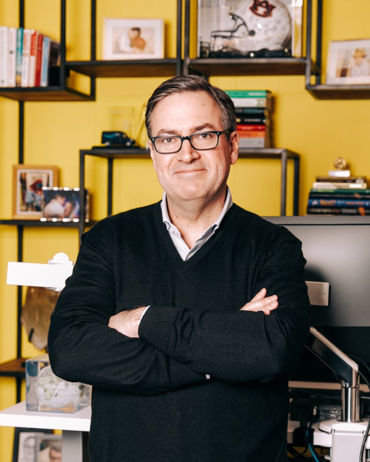 Dave Clark stands in an office with his arms crossed, posed for a portrait