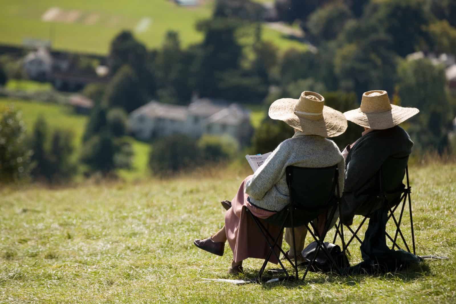 Two elderly people relaxing in the summer sunshine Box Hill near Dorking Surrey England