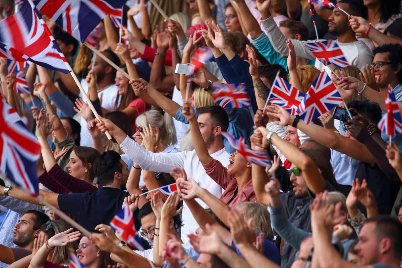 UK coloured flags waving above large crowd on a stadium sport match.