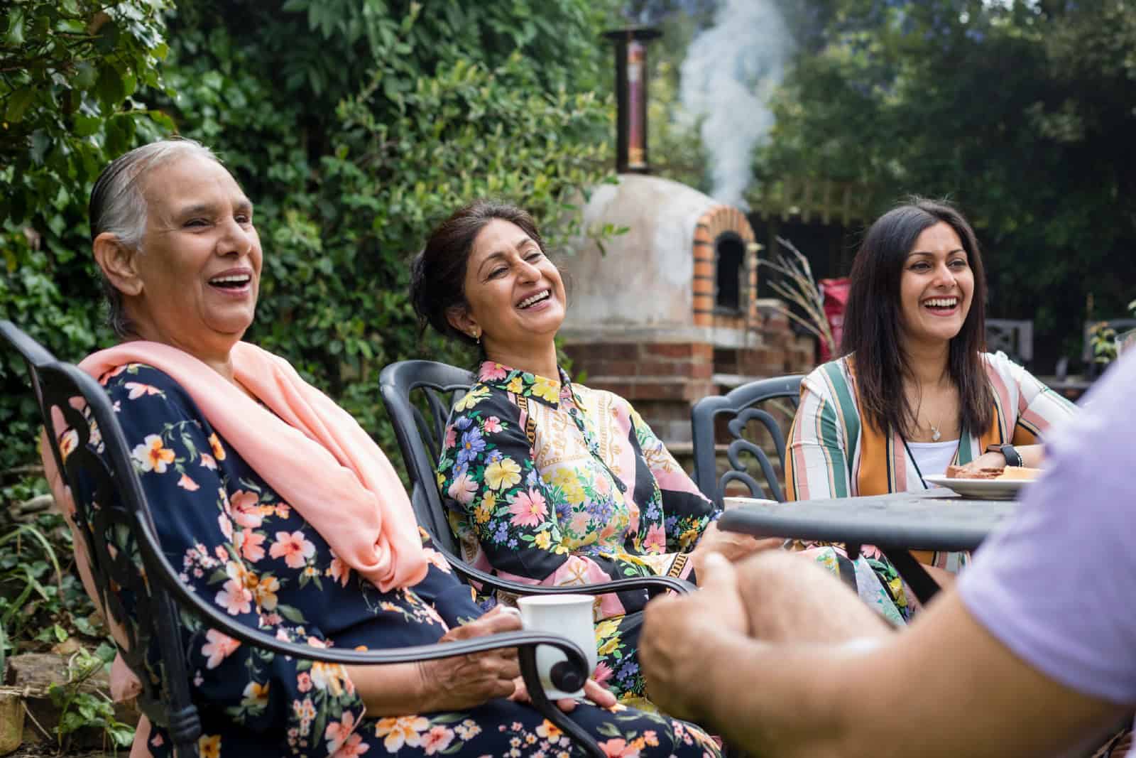 Pakistani multi generation family sitting around a table in a garden in Middlesbourgh, North East of England.