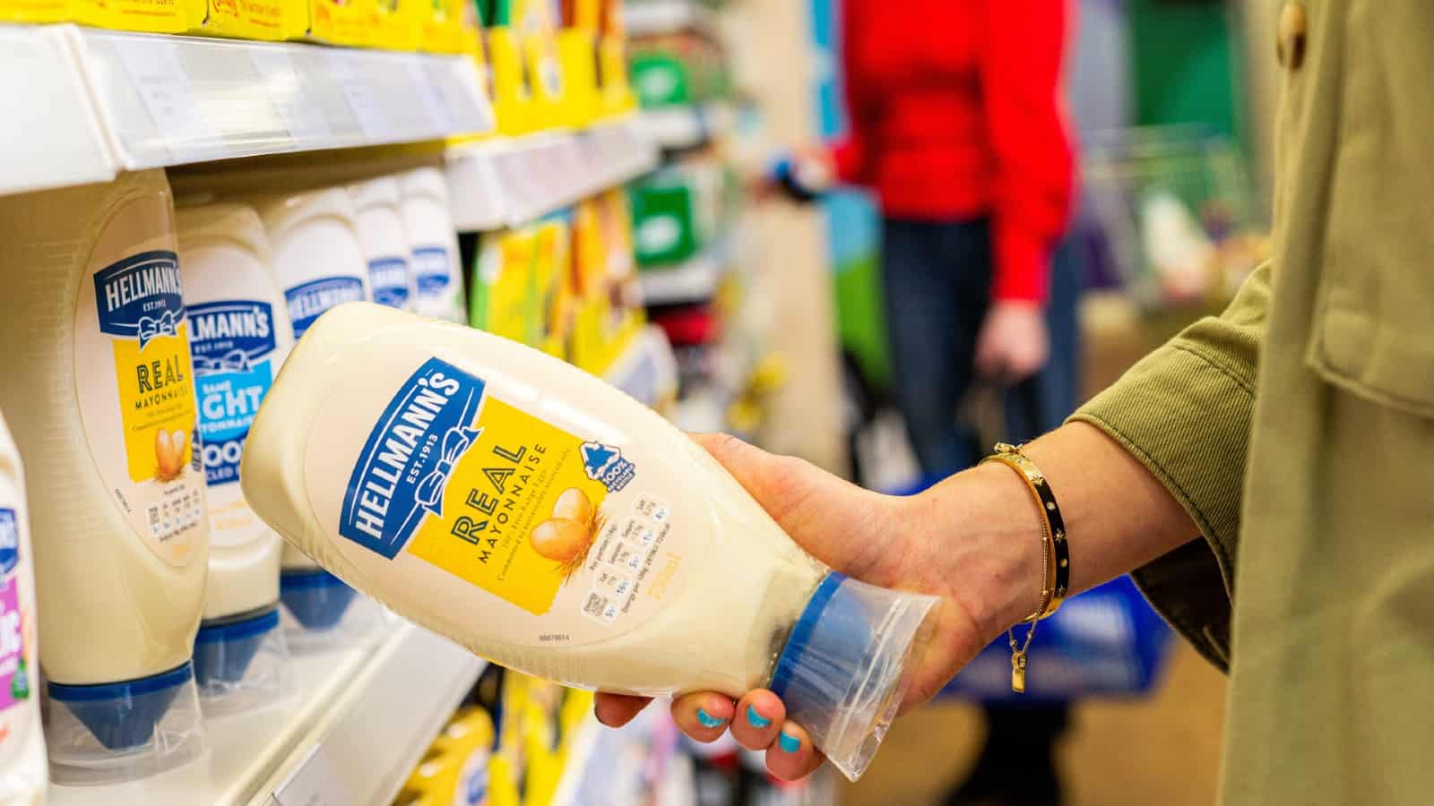 Lady taking a bottle of Hellmann's Real Mayonnaise from a supermarket shelf