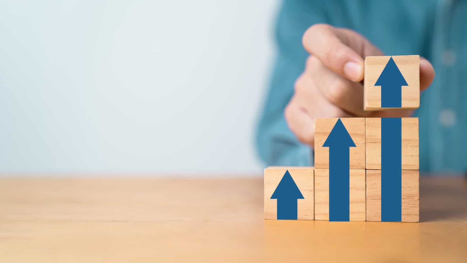 Businessman hand stacking up arrow on wooden block cubes
